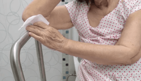 Elderly woman gripping a bathroom safety handle